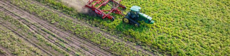 Tractor working across cultivated farm rows