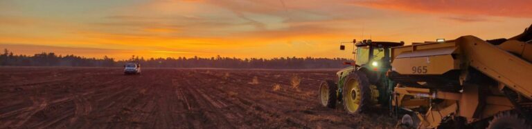 Tractor working in field at sunset