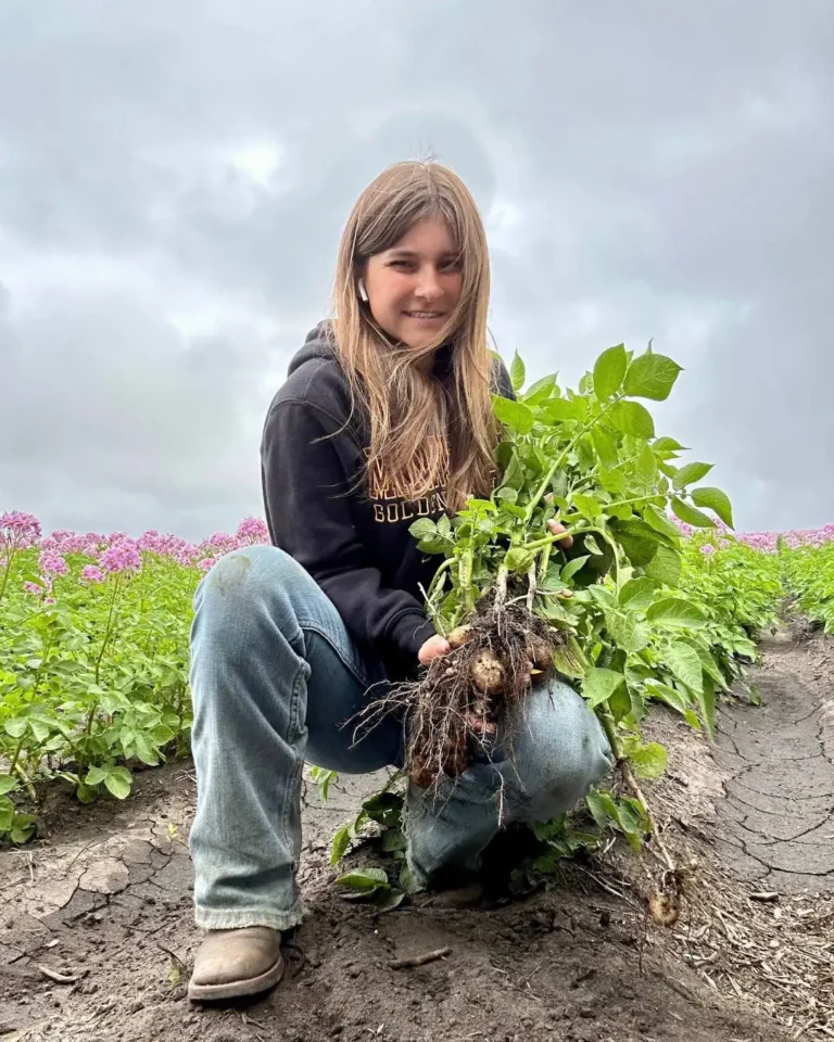 Young woman holding freshly harvested vegetables in field