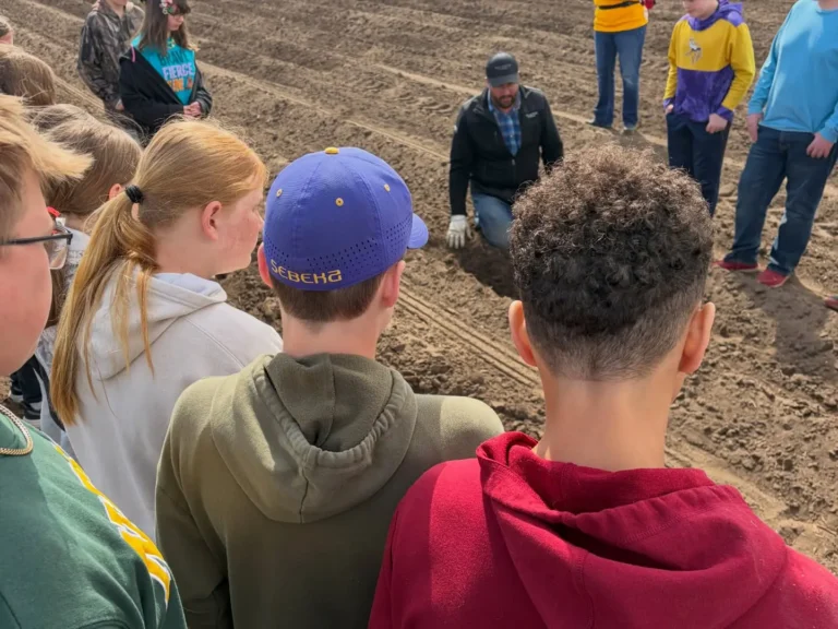 Students gathered around potatoes during a farm tour