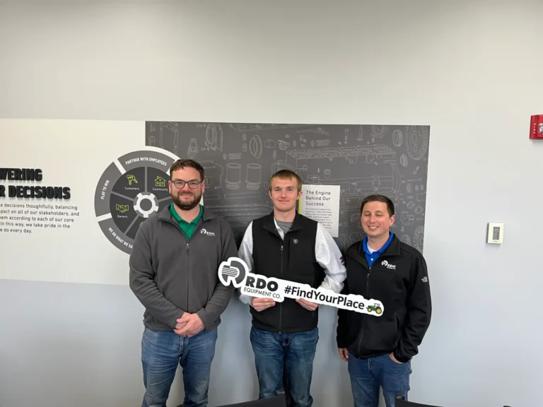 Logan standing with two other people, holding an oversized key